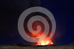 Etna in eruzione con grandi emissioni di cenere dal cratere del vulcano nel ciel notturno stellato