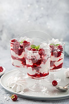 Eton mess, traditional english dessert, meringues, whipped cream, berry sauce and fresh raspberry in  glass