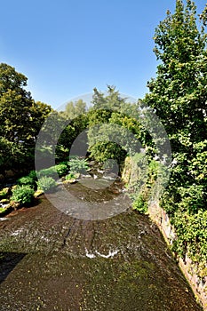 Alb river flowing through Ettlingen in summer with trees and blue sky in Germany