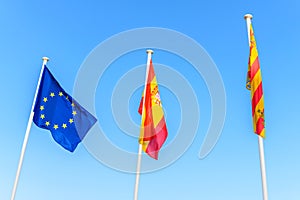 EU flag Spanish flag local Ibiza flag waving in the wind on blue sky background