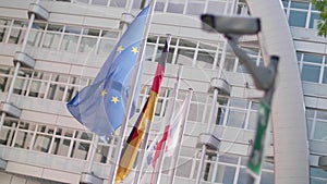 EU flags wave behind a cctv security camera