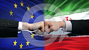 EU vs Iran conflict, international relations crisis, fists on flag background