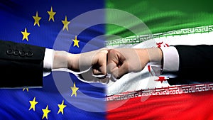 EU vs Iran conflict, international relations crisis, fists on flag background