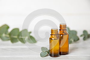 Eucalyptus essential oil in a glass bottle with green eucalyptus leaves