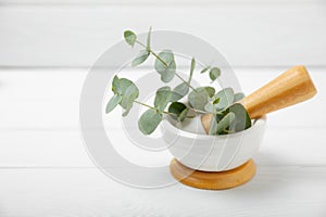 Eucalyptus leaves and mortar on a wooden background.