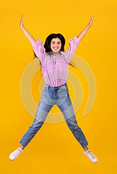 Euphoria concept. Full length portrait on positive armenian woman jumping and fooling on yellow background, crop