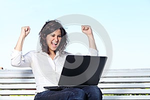 Euphoric businesswoman with a laptop sitting on a bench