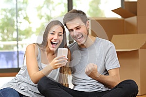 Euphoric couple moving house and watching phone