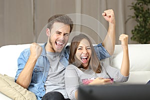 Euphoric couple watching tv at home photo