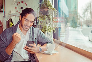 Euphoric man pumping fist while looking at mobile smartphone