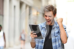 Euphoric winner man with a tablet photo