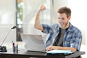 Euphoric winner man using a laptop at home photo