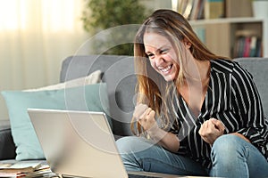 Euphoric woman celebrating success checking laptop content photo