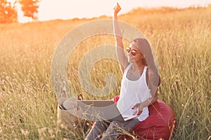Euphoric woman searching job with laptop in a meadow