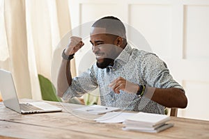 Euphoric young black man celebrating online lottery win.