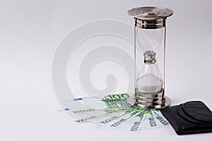 Euro banknote, black purse and hourglass on a white background. Time is money-concept.