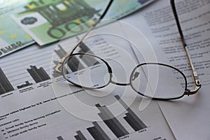 100 Euro banknote, glasses, pen and financial diagrams report. business concept
