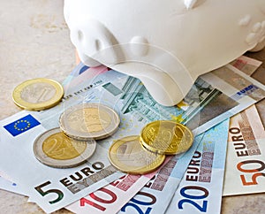 Euro banknotes and coins with piggy bank