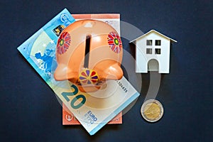 Toy House, piggy bank and euro on black background