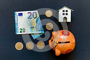 Toy House, piggy bank and euro on black background