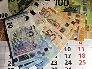 Euro banknotes of different denominations on a calendar with a date, the concept of saving money