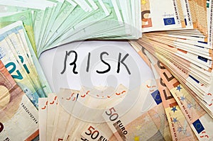 Euro banknotes and the inscription `risk` on white. Business concept.