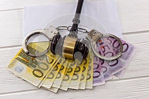 Euro banknotes with judge`s gavel and handcuffs