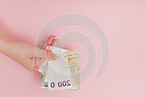 Euro banknotes money in female hands on pink background