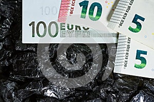 Euro banknotes on raw coal nuggets, bills on coal, power of money and ore