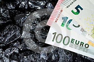 Euro banknotes on raw coal nuggets, bills on coal, power of money and ore