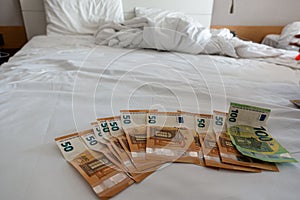 euro banknotes are spread out on a bed with a white duvet cover