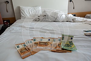 euro banknotes are spread out on a bed with a white duvet cover