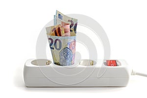 Euro banknotes stuck in an electric triple power strip, concept of increasing energy costs, home finances and saving money on