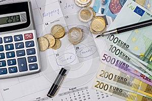 Euro bills, calculator, ink pen and coin on calendar background