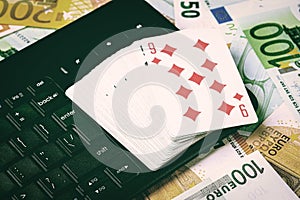 Euro bills, a deck of playing cards and a black keyboard. Concept of card games, casino or poker online.