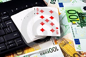 Euro bills, a deck of playing cards and a black keyboard. Concept of card games, casino or poker online