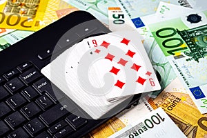 Euro bills, a deck of playing cards and a black keyboard. Concept of card games, casino or poker online