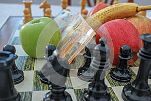 euro bills and fruits among chess pieces