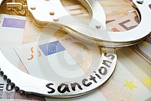 Euro bills and handcuffs with sanctions. Economical restrictive measures. photo
