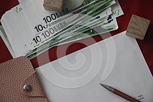 100 euro bills, pink leather wallet, pen and blank paper with copyspace. Business profit financial concept