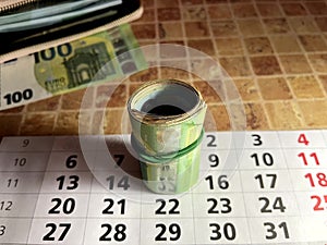 Euro bills rolled into a tube on a calendar with dates the concept of saving money