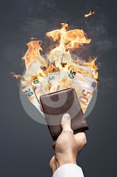 Euro bills in a wallet burning with a bright flame