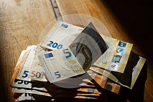 Euro bills on a wooden table.Euro banktons on a table in a strip of light.Income in European countries.