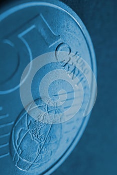 A 5 euro cent coin close-up. Dark blue vertical background about money, economy or finance of countries of the European community