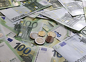 Euro cent coins on the background of 100 Euro banknotes arranged in random order