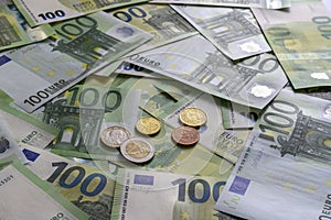 Euro cent coins on the background of 100 Euro banknotes arranged in random order