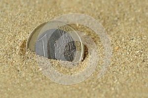 Euro coin covered by sand - Concept of finance and business