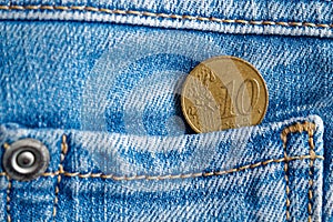 Euro coin with a denomination of 10 euro cent in the pocket of old worn blue denim jeans