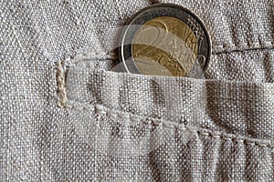 Euro coin with a denomination of 2 euros in the pocket of worn linen pants