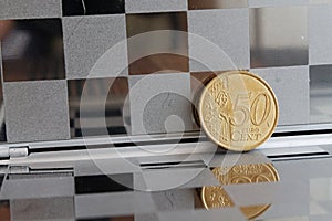 Euro coin with a denomination of 50 euro cents in mirror reflect wallet, chequered background